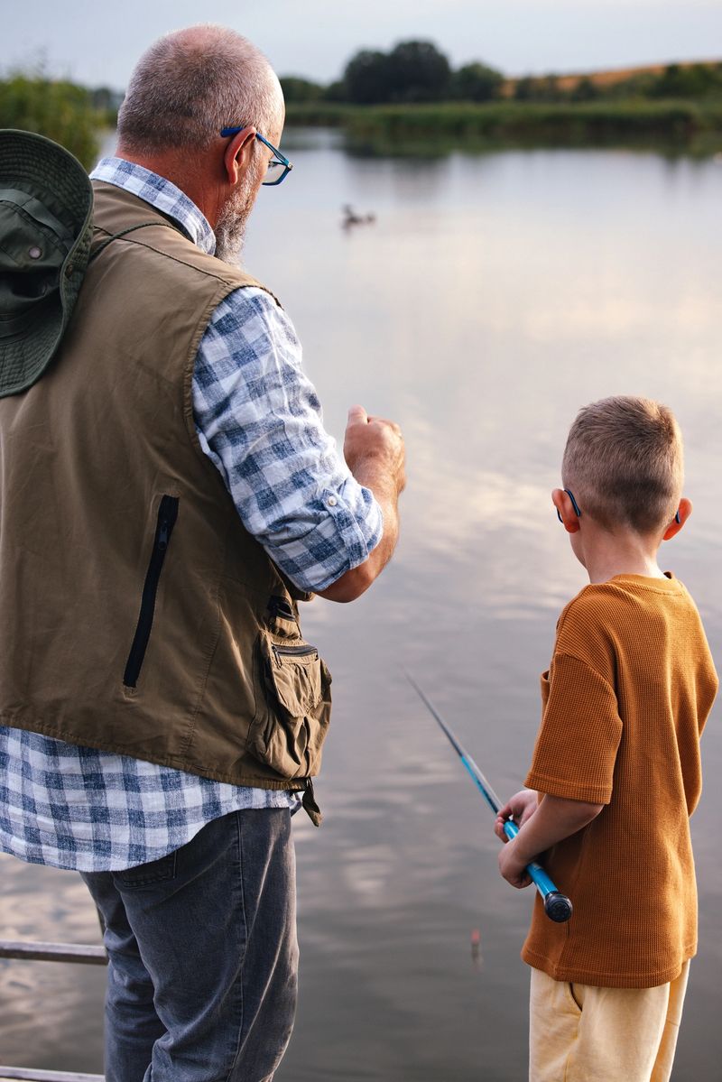 A heartwarming scene of a grandfather and his grandson enjoying a fishing trip at a serene lake, highlighting family bonds and outdoor leisure.