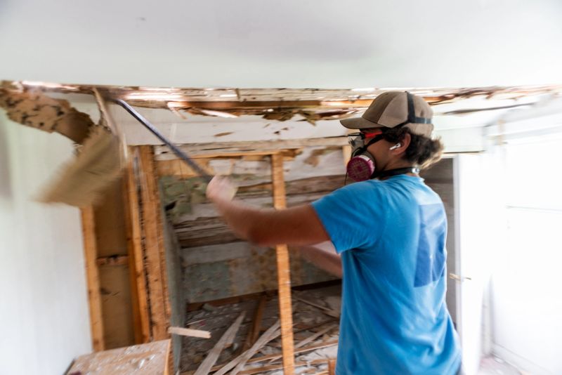 A person working on the ceiling of an old home during a major renovation.