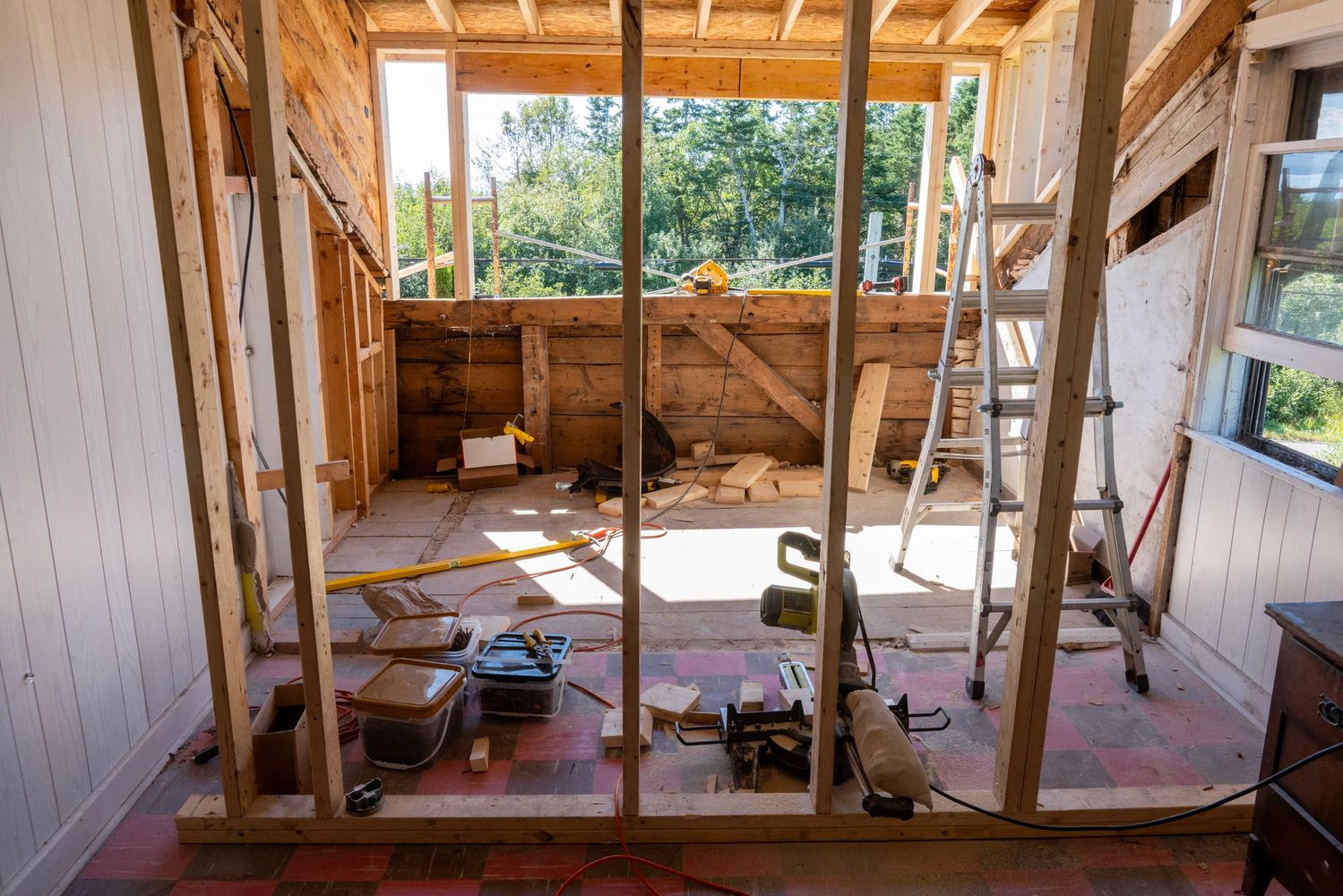 Interior of a room under renovation with wooden framing and tools scattered.