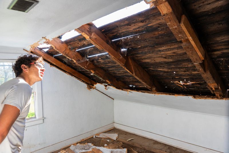A person working on the ceiling of an old home during a major renovation.