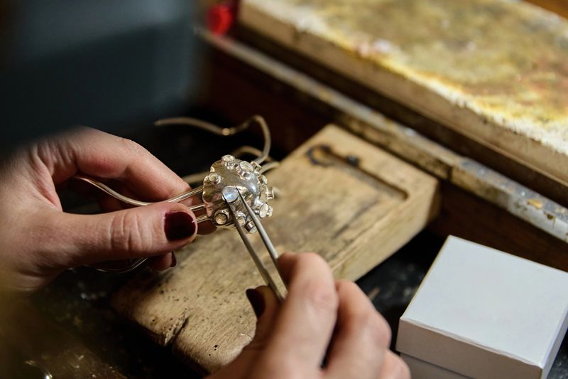 Jeweler working on handmade silver jewelry with gemstones and tweezers
