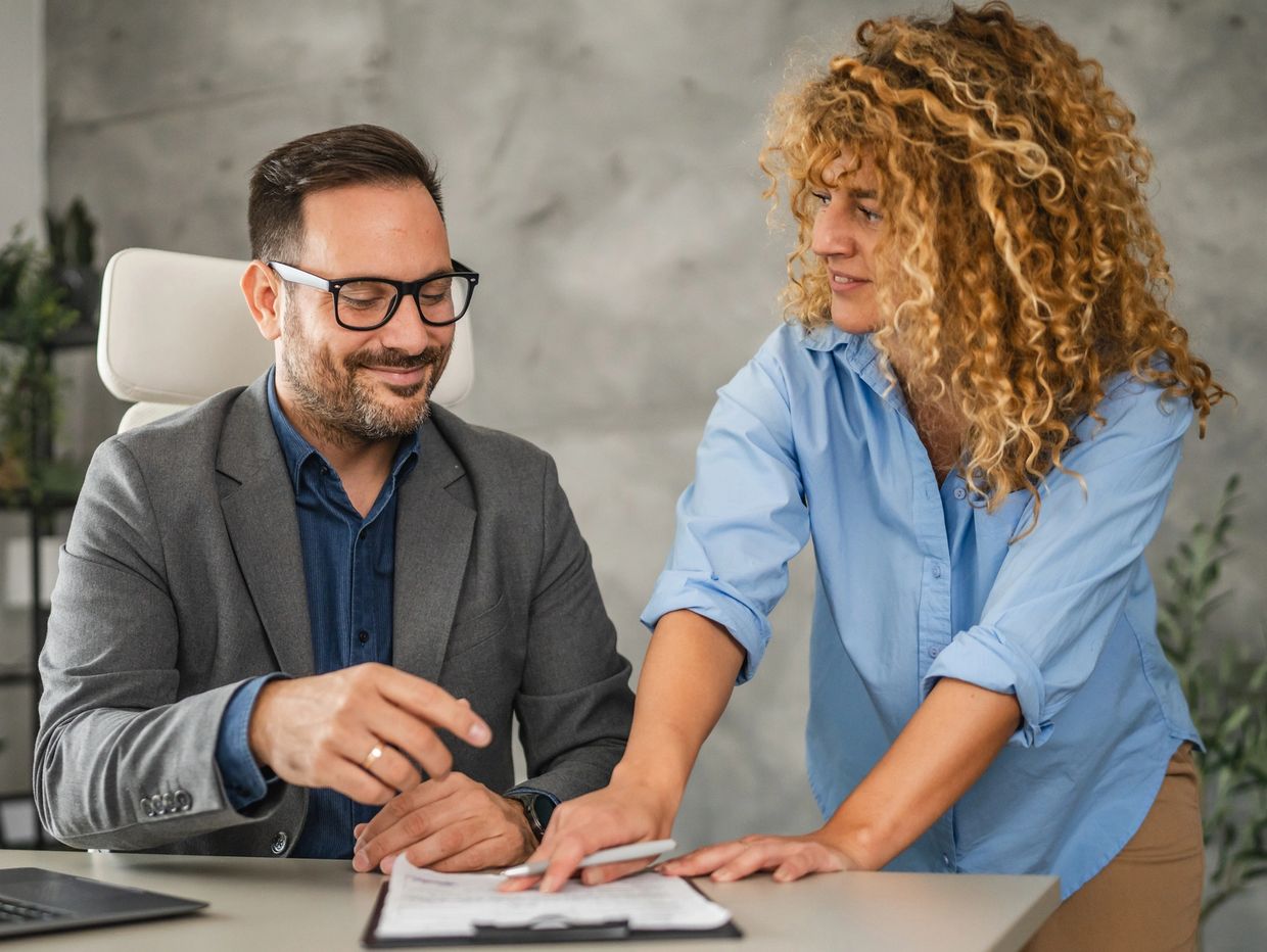 Two colleagues discussing documents in a modern office setting.