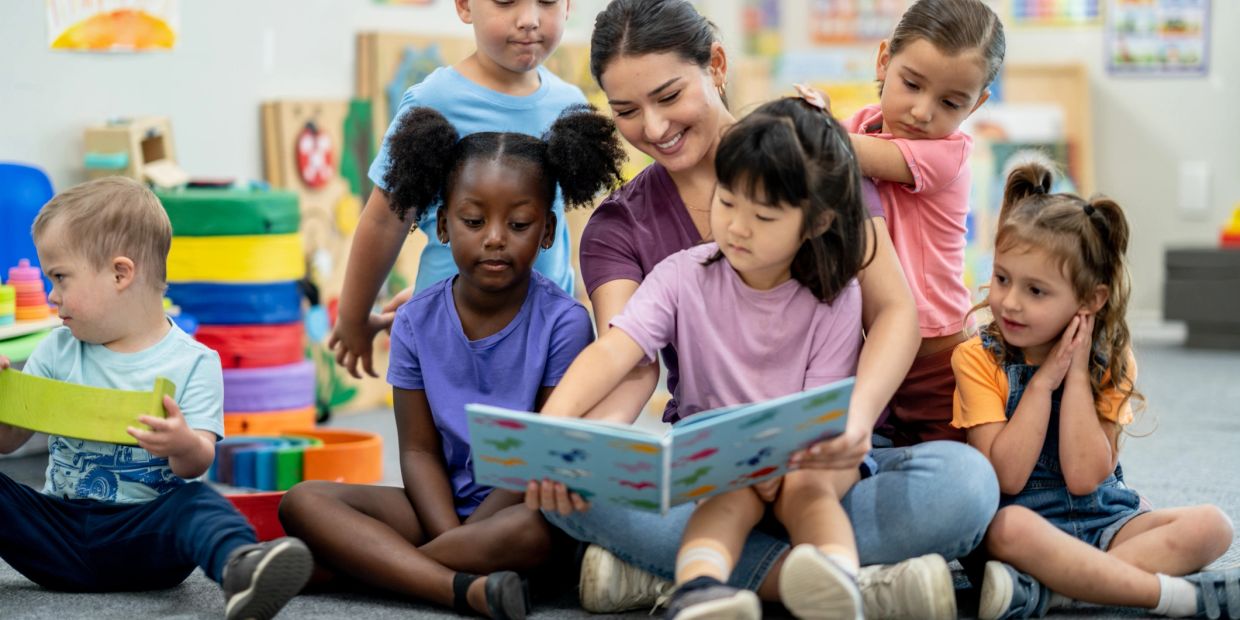 Teacher reading to diverse children in a classroom.