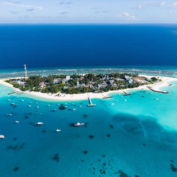 Aerial view of a small island with clear turquoise water and boats.