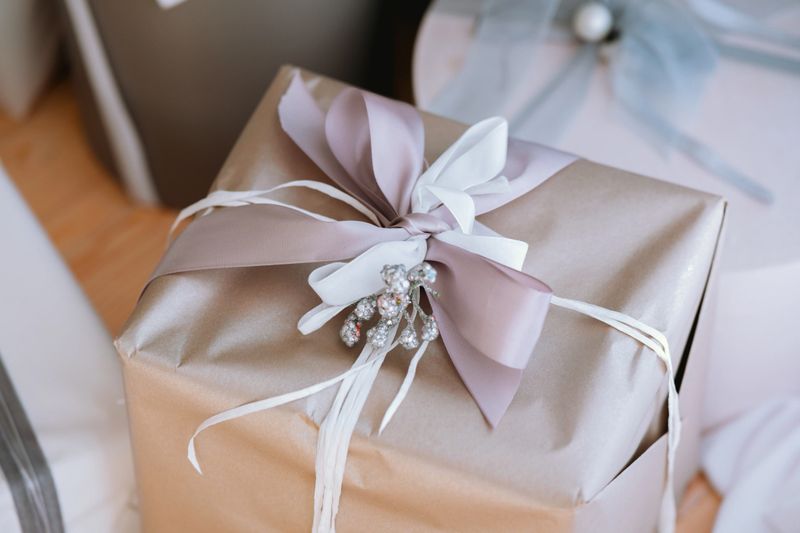 A beautifully wrapped gift sits on a table, featuring elegant ribbon and decorative accents. The atmosphere suggests a special occasion, perfect for a celebration or holiday event.
