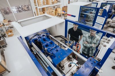 Two men inspect a large industrial machine in a factory.