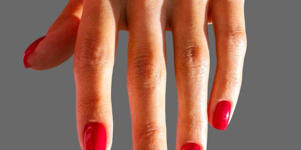 Hand with red painted nails against a gray background.