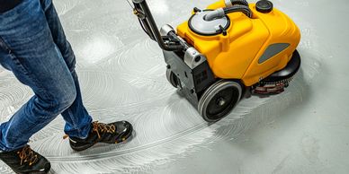 Person operating a floor cleaning machine on a soapy surface.
