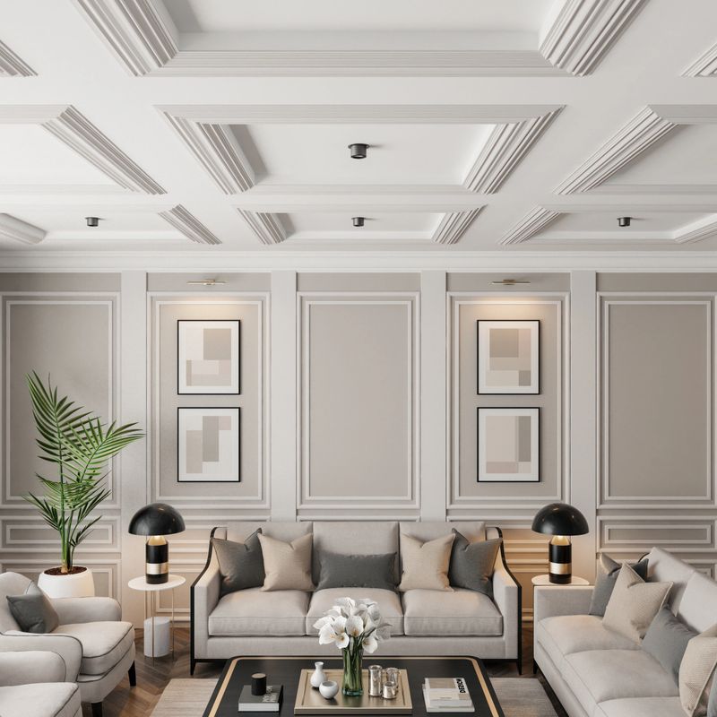 Experience the charm of modern neo-classical Parisian interior design with this luxurious living room setup. The space features classic wall moulding plaster design and large classic windows that flood the room with natural light. The sophisticated beige color palette is complemented by plush pillows and sleek modern furniture. A stylish living room table with golden accents and a striking vase filled with white flowers add the finishing touches. This image is ideal for showcasing modern furniture, elegant decor, clean design, cozy room ideas, and renovation projects with a modern classic style.