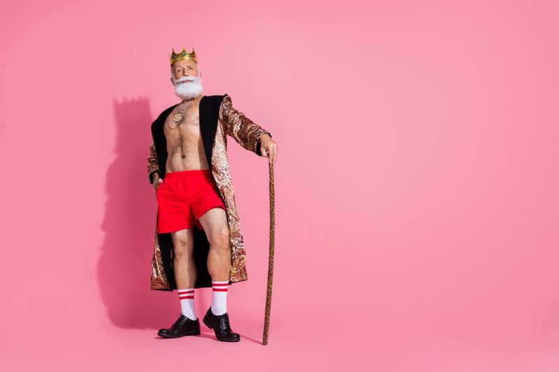 Photo of eccentric man king in trendy leopard bathrobe presenting promo banner poker game winning empty space on pink color background.