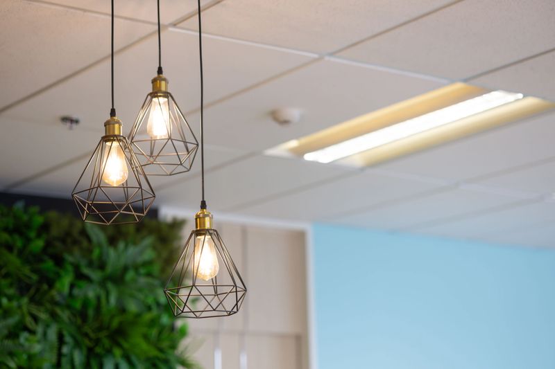 Three lamps with a wire frame are hanging from the ceiling, illuminating the room. The lamps are lit up, creating a warm and inviting atmosphere