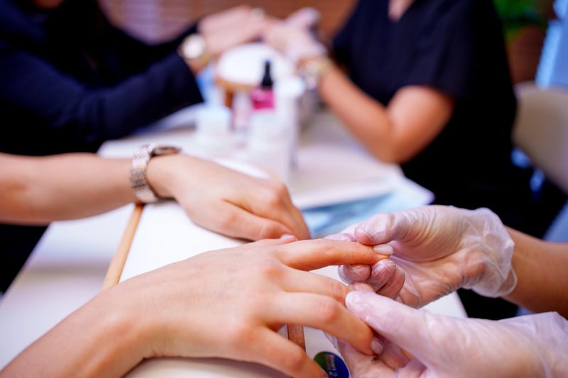Women having  manicure at beauty spa, She drips nail care serum onto the fingernail and spreads it over the entire nail