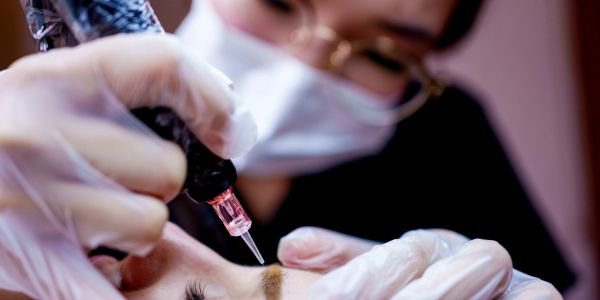 Close-up of person getting permanent makeup eyebrows.