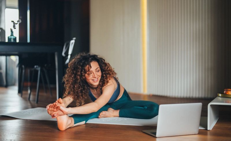 Female exercising yoga at home with online video class