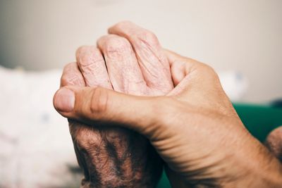 A younger hand gently holding an elderly hand, symbolizing care and support.