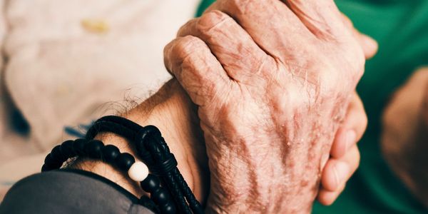 An elderly hand warmly holding a younger hand, symbolizing care and support.