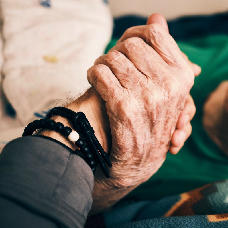 A man holding hands with a 90 year old senior man.
