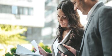 Two professionals reviewing documents outdoors in a business setting.