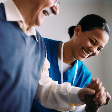 Nurse and elderly man sharing a joyful moment while holding hands.