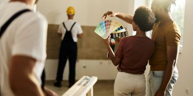 Couple selecting paint colors while workers prepare a room.