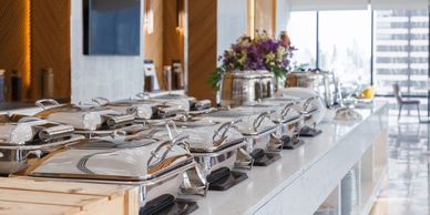 Buffet chafing dishes lined up on a marble counter.