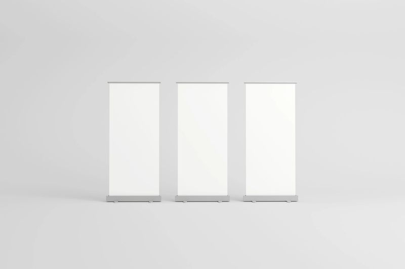 Three empty roll-up banners with white backgrounds, lined up side by side, ideal for customizable branding in exhibitions, trade shows, or promotional events.