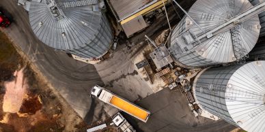 Aerial view of a grain processing and storage facility with large silos and transport trucks.