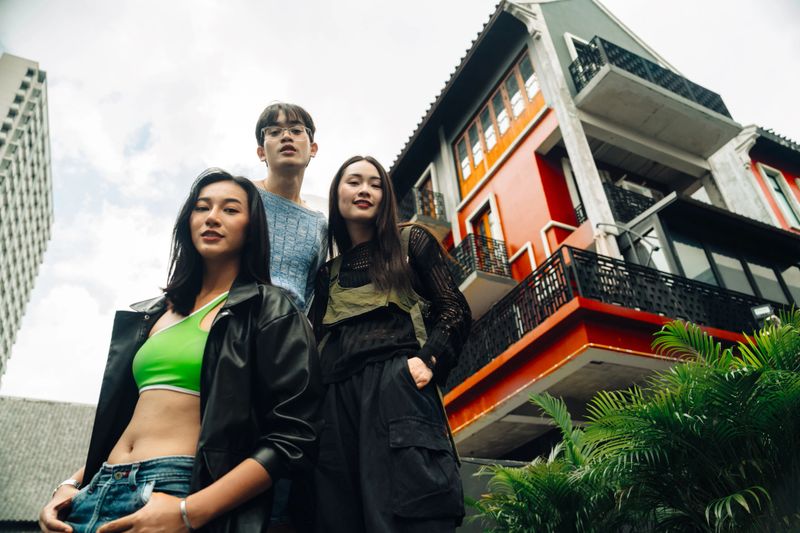 Group portrait of trendy young adults in city setting, exuding confidence and style against a modern building backdrop. Ideal for urban fashion and lifestyle themes.