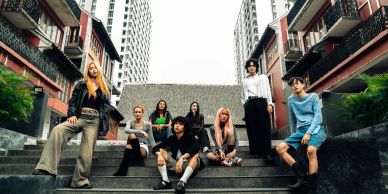 Group of eight young people posing on outdoor stairs.