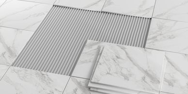 White marble floor tiles being installed with adhesive spread underneath.