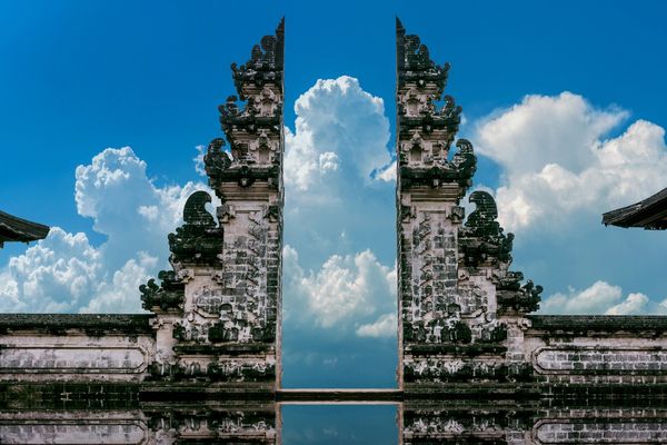 Ancient stone gate with intricate carvings under a bright blue sky.