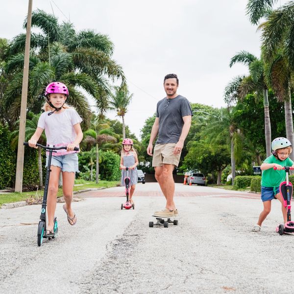 Family enjoying outdoor scootering and skateboarding.