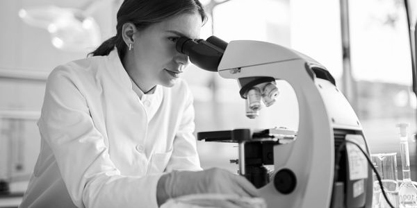 Scientist examining samples through a microscope in a lab.