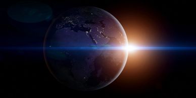Sunrise over Earth with city lights visible on the dark side.