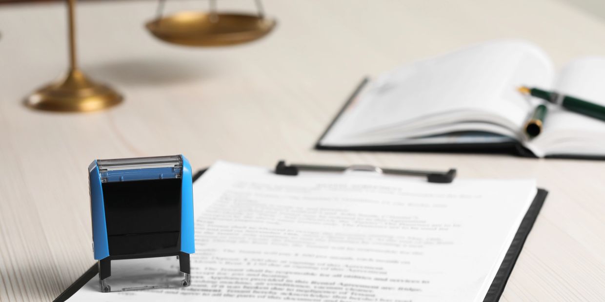 Office desk setup with a stamp, documents, and scales of justice.
