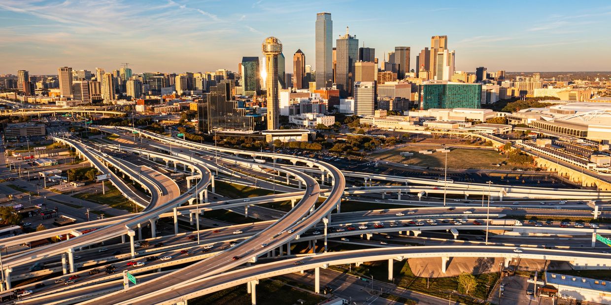 Dallas skyline with intricate freeway system under a clear sky.