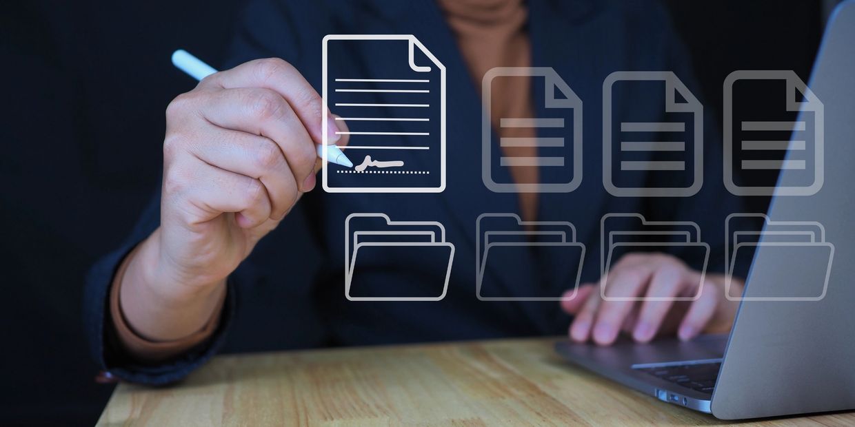 Person digitally signing a document on a laptop with virtual file icons.