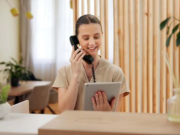 The image shows a smiling woman, likely a receptionist or front desk staff member