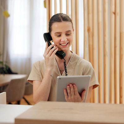 Smiling woman talking on the phone while holding a tablet.