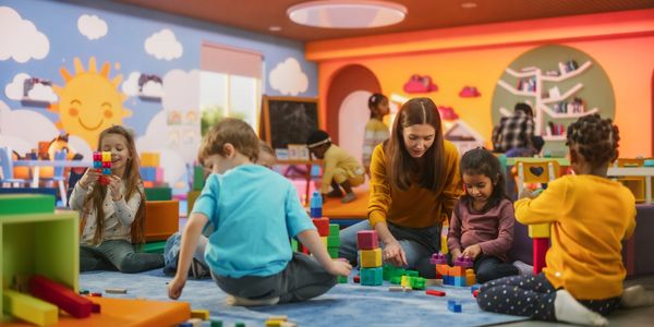 Children and a teacher playing with colorful blocks in a vibrant classroom.