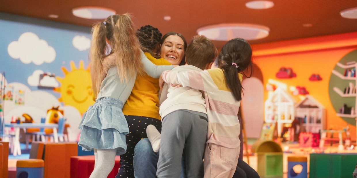 Group of kids hugging their tutor.