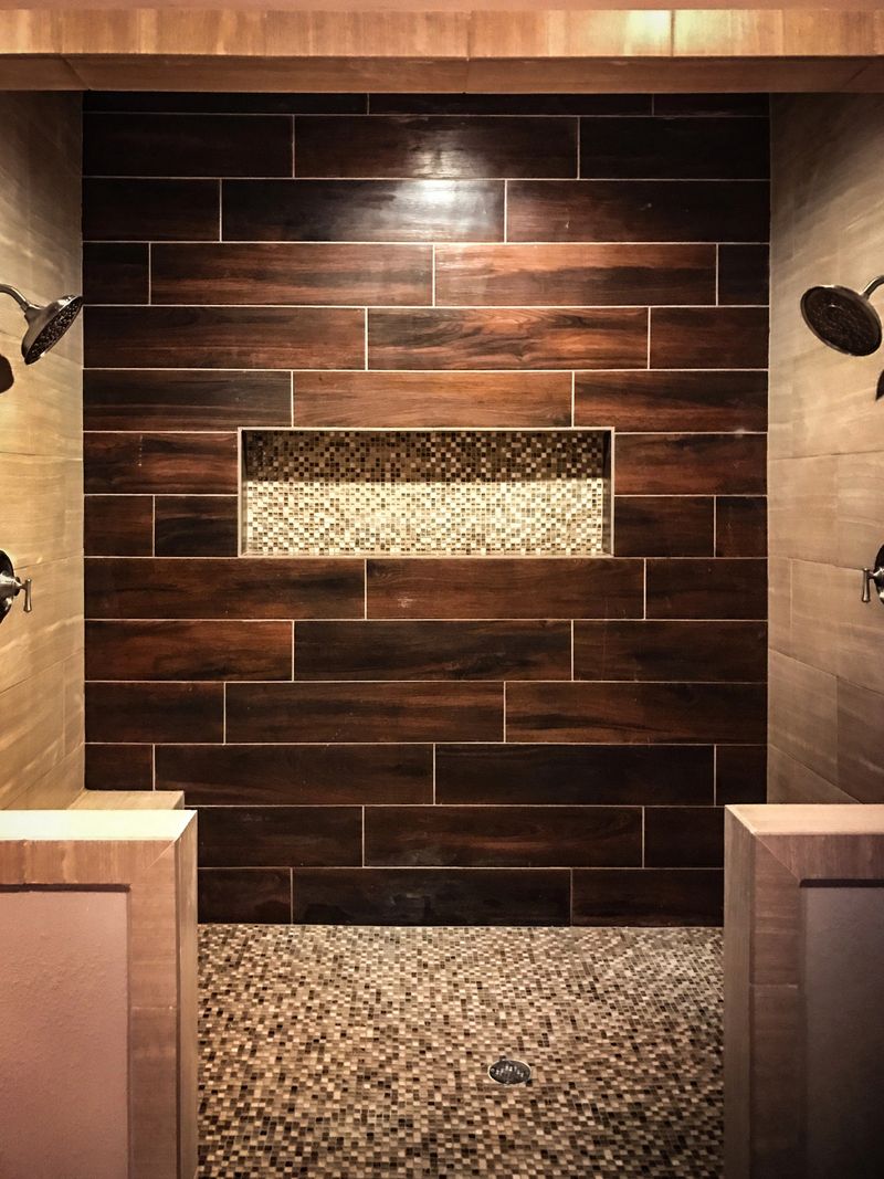 Dual shower heads in oversized shower with woodgrain tile and pebble floors