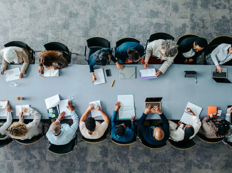Top view of diverse business group in office meeting, collaborating and discussing around a large table.