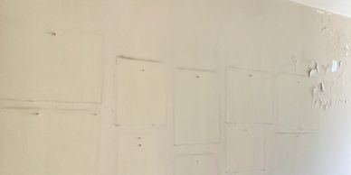 Faded outlines and peeling paint on an old beige wall.