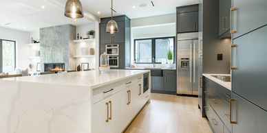Modern open-concept kitchen remodel featuring a large white island, grey cabinets, and stainless ste