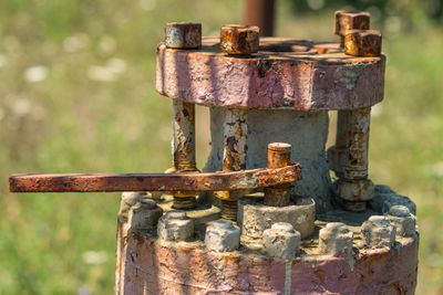 Close-up of a rusty industrial valve with bolts and a lever.