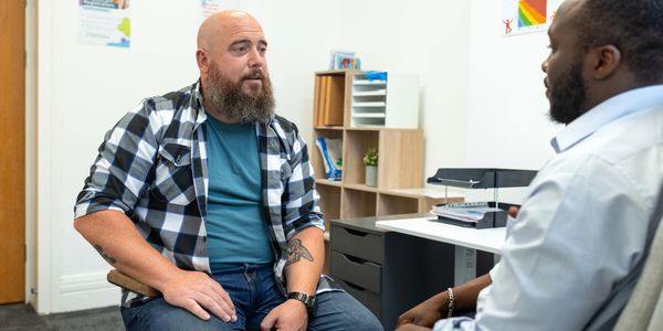 Two men engaged in a serious conversation in an office setting talking about health.