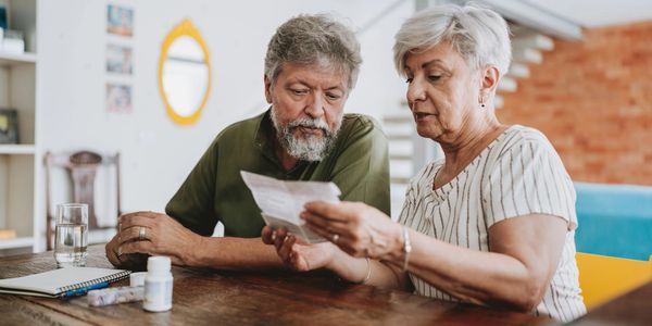 An elderly couple reviews medical documents at home.