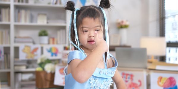 A young girl with bows in her hair gives a thumbs-up.