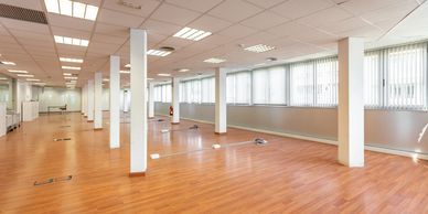 Spacious empty office with wooden floors and large windows.
